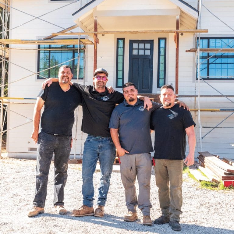 four men standing in front of a home construction site.