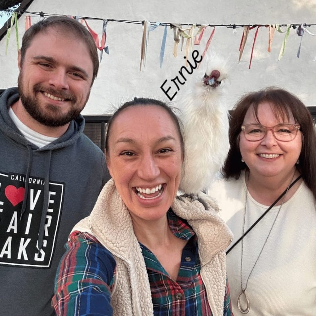 three people with a white rooster