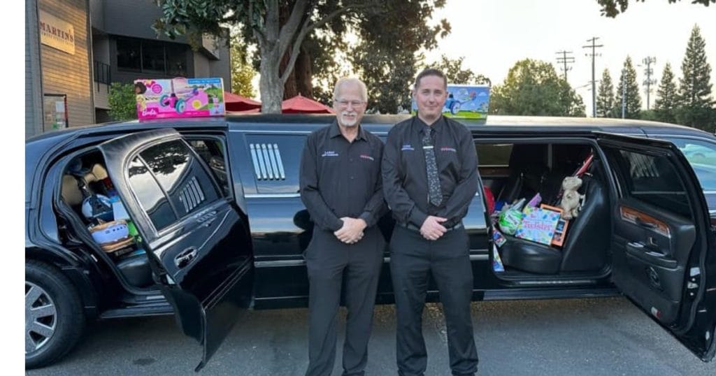 two men in front of limo filled with toys