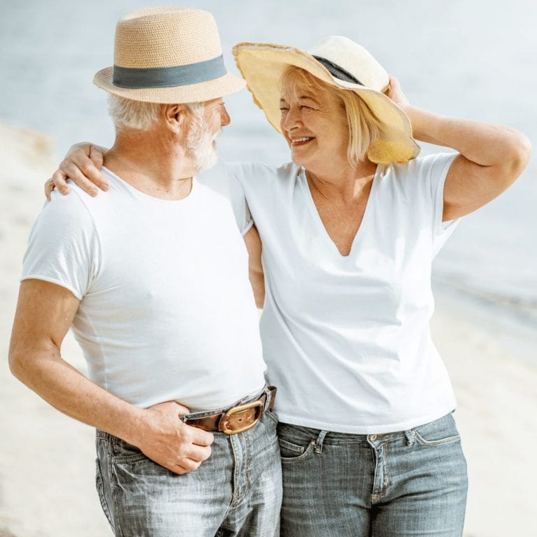 older man and women in white tees wearing hats