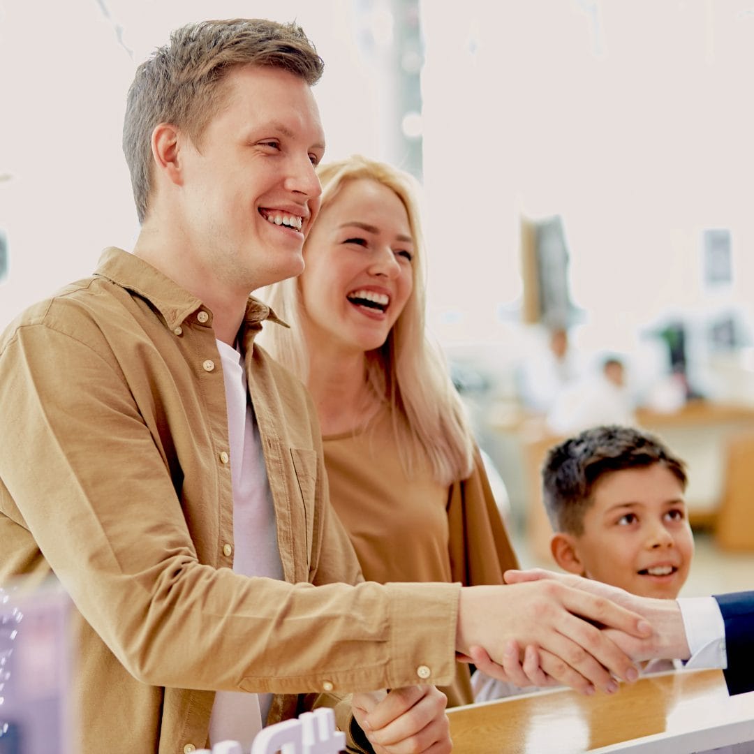 man shaking hands while smiling woman and little boy stand next to him
