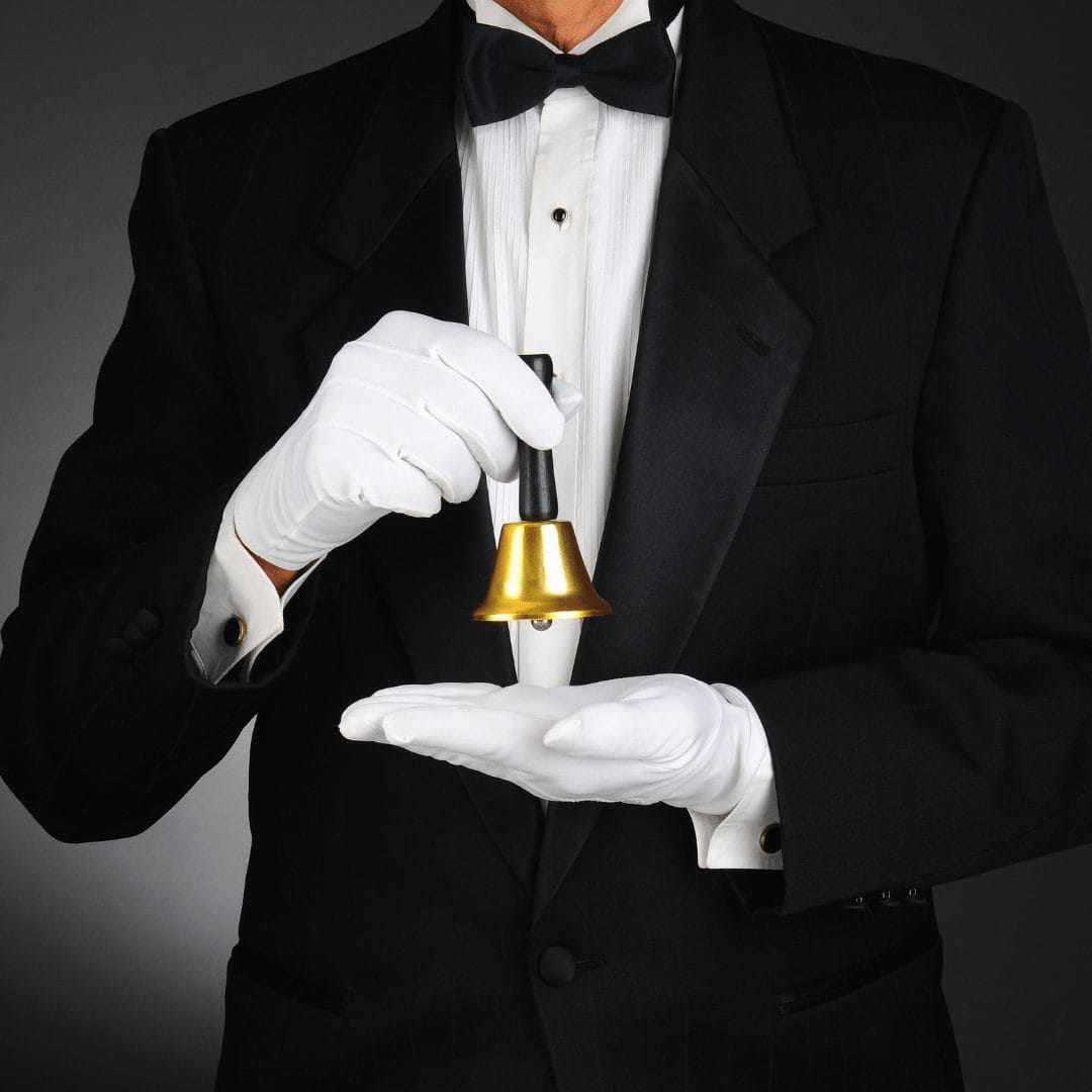 man in suit with white gloves ringing a bell